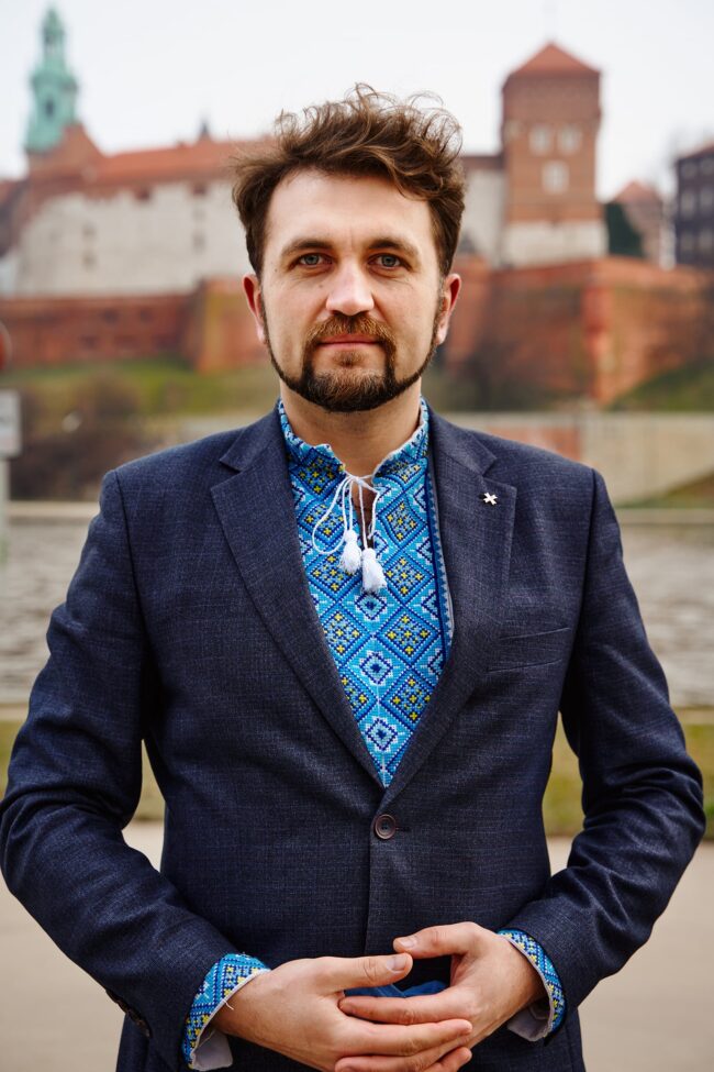 Andriy Oliynyk mężczyzna z brodą, w niebieskiej marynarce i koszuli wyszywanej