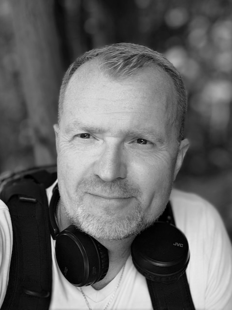 Piotr Kołodziej mężczyzna w średnim wieku ze słuchawkami na szyi